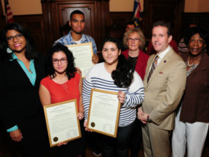 Xavier Reyes holding his certificate in the rear center of this photo; Also pictured (from left to right) are Essex County Freeholder President Britnee Timberlake, Carmen Franco and Virginia Cardona (NJAC Foundation & Investors Bank Scholarship Award recipients), Freeholder Patricia Sebold, Freeholder Vice President & NJAC Secretary-Treasurer Brendan Gill, and Freeholder Lebby Jones